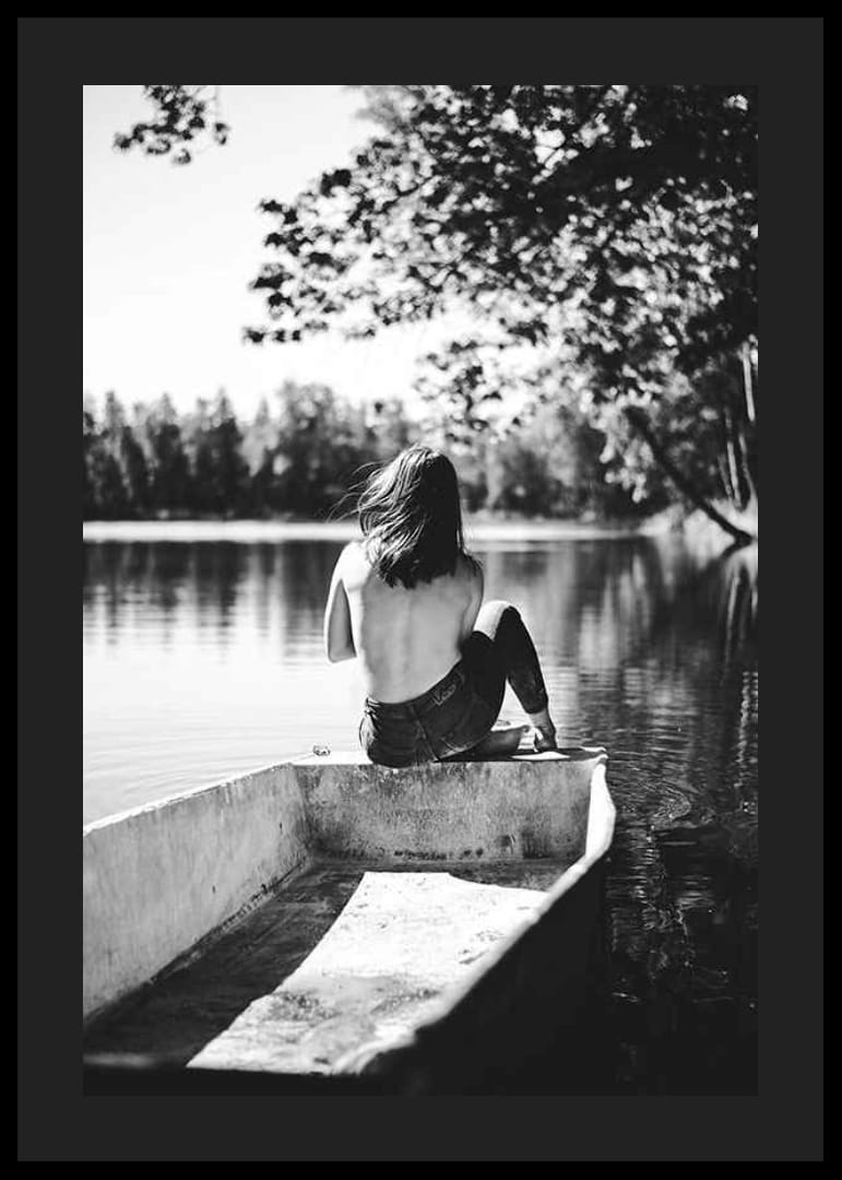 Fotografía en blanco y negro de una mujer en un bote en un lago tranquilo con árboles.-12