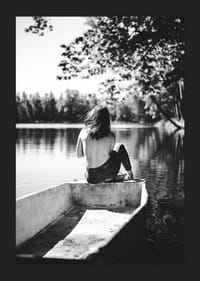 Fotografía en blanco y negro de una mujer en un bote en un lago tranquilo con árboles.-5