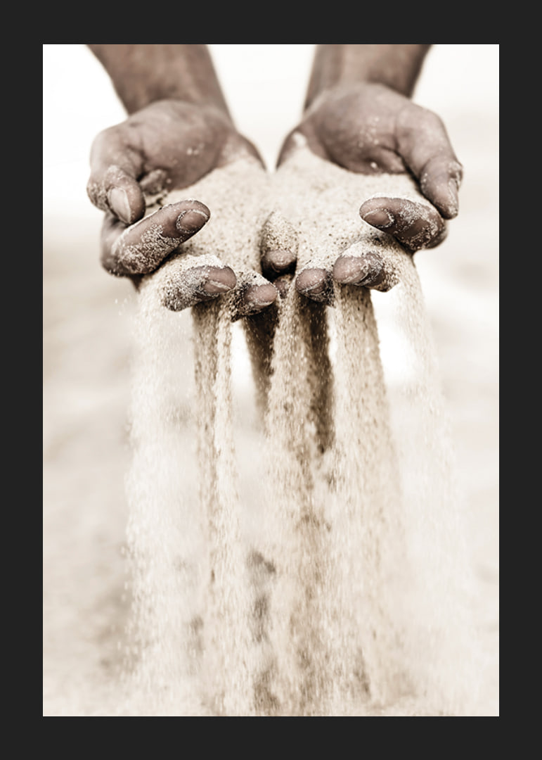 Photographie de mains libérant du sable dans des tons beiges doux-12
