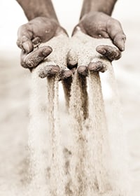Photographie de mains libérant du sable dans des tons beiges doux-7