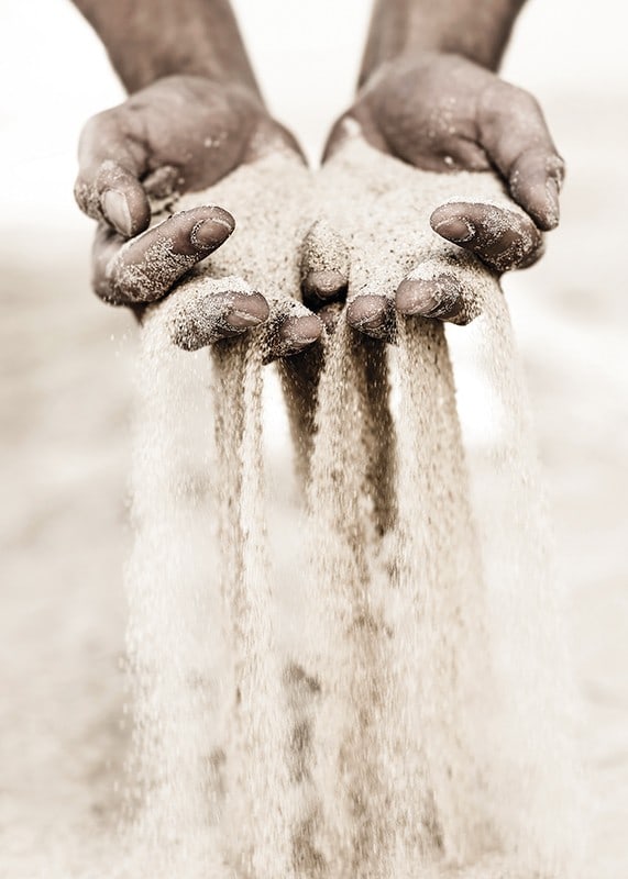 Photographie de mains libérant du sable dans des tons beiges doux-12