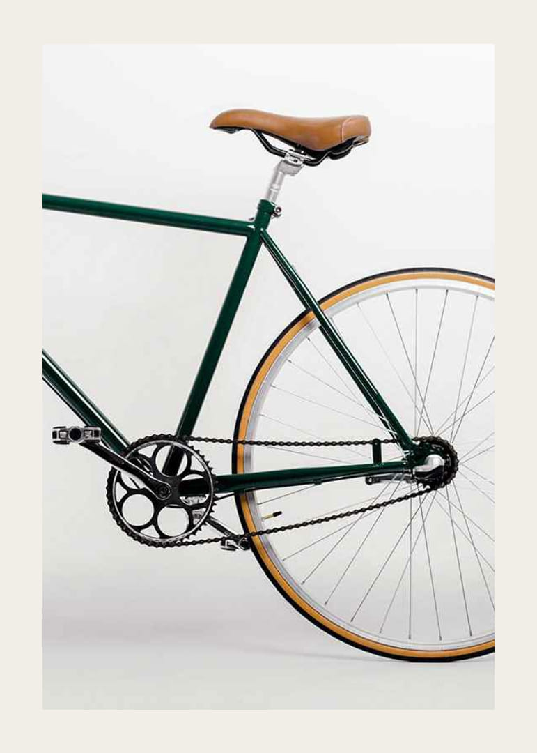 Photograph of green bicycle with brown saddle against light background-12