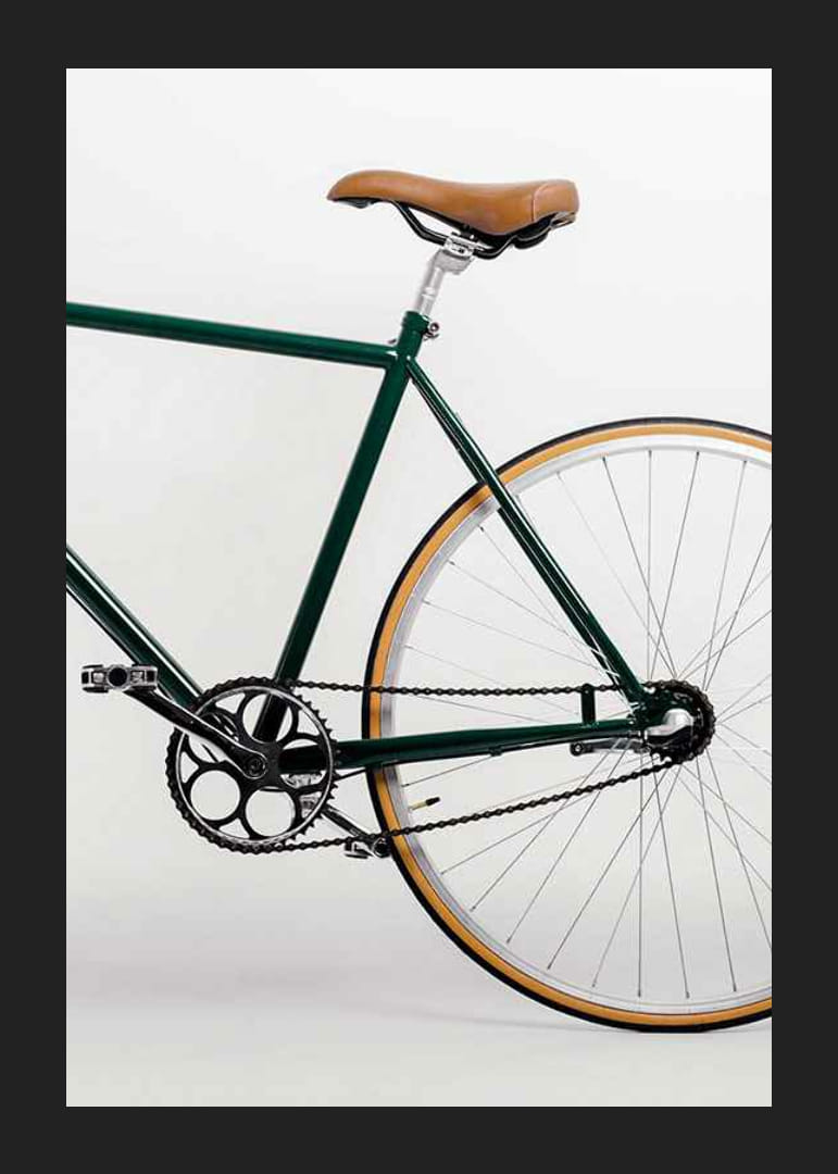 Photograph of green bicycle with brown saddle against light background-12