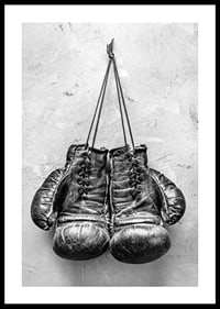Black and white worn boxing gloves against rough wall-0