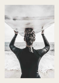 Foto van een surfer van achteren met een board boven zijn hoofd in de oceaan-3