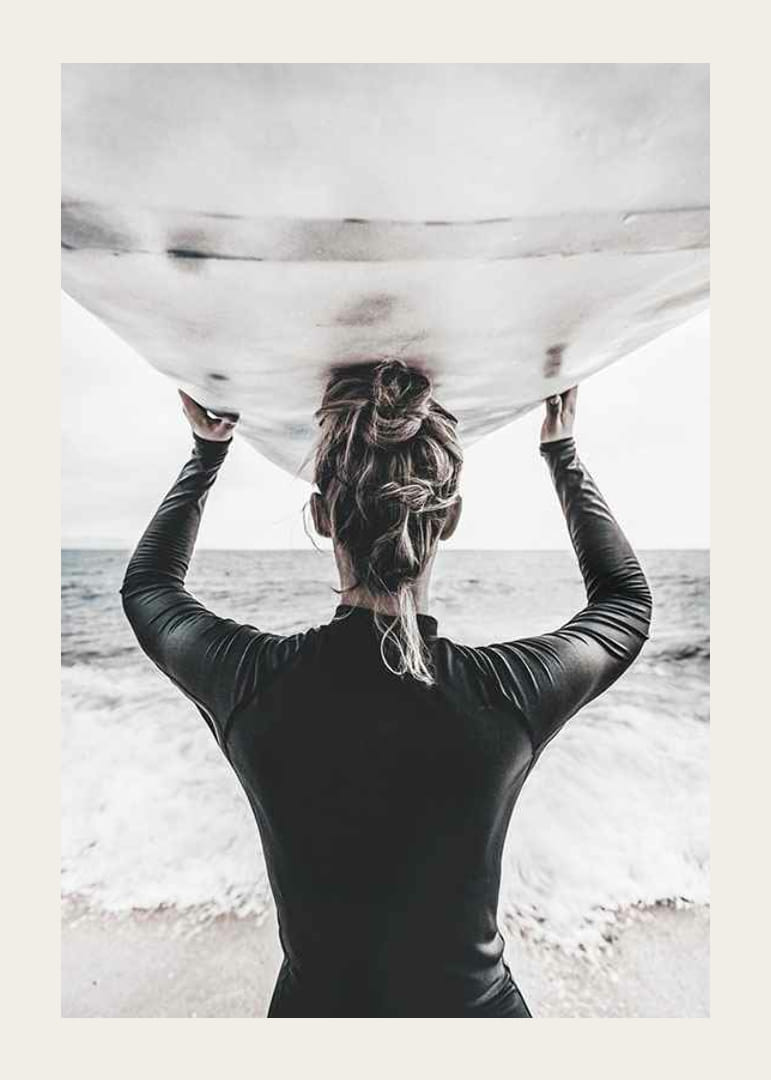 Foto van een surfer van achteren met een board boven zijn hoofd in de oceaan-12