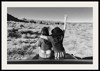 Black and white photograph of two girls on car hood in front of open nature-2