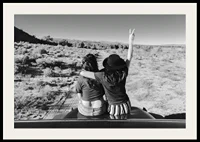 Black and white photograph of two girls on car hood in front of open nature-2