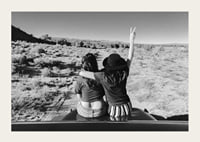 Black and white photograph of two girls on car hood in front of open nature-3