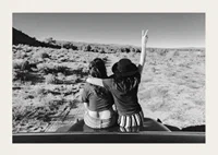 Black and white photograph of two girls on car hood in front of open nature-3