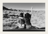 Čiernobiela fotografia dvoch dievčat na kapote auta pred otvorenou prírodou-3