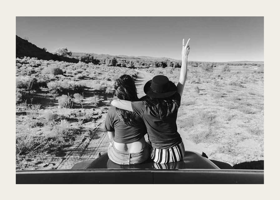 Čiernobiela fotografia dvoch dievčat na kapote auta pred otvorenou prírodou-12