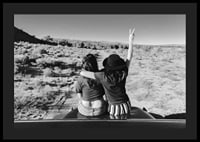 Black and white photograph of two girls on car hood in front of open nature-4
