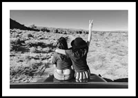 Black and white photograph of two girls on car hood in front of open nature-0