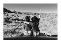 Black and white photograph of two girls on car hood in front of open nature-1