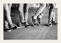 Čiernobiely detailný záber štyroch mladých ľudí v džínsoch a teniskách-3