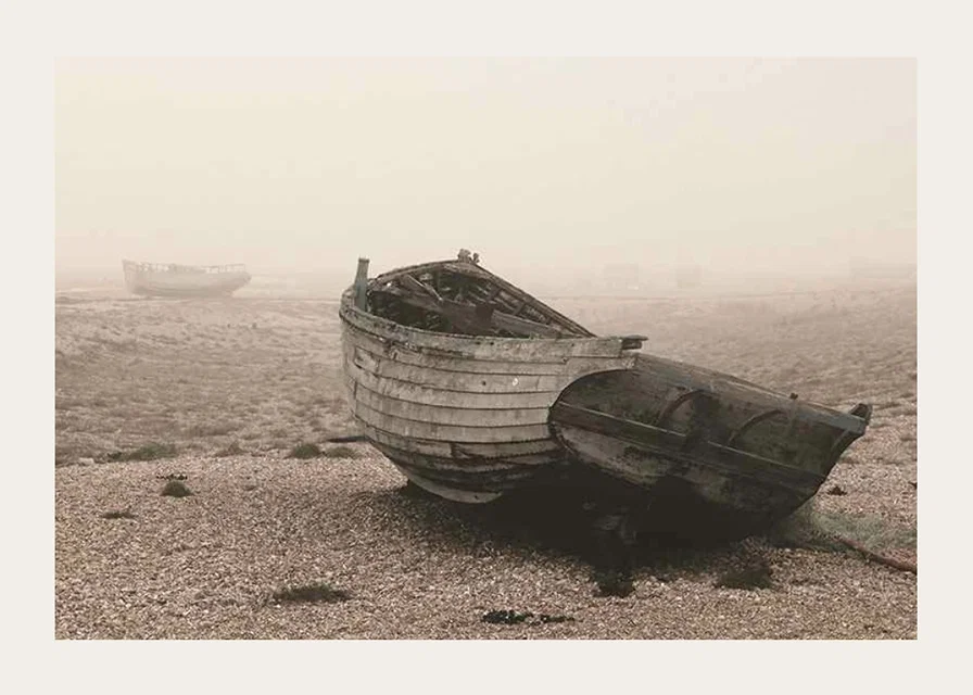 Photograph of old wooden boat on rocky beach in fog-12