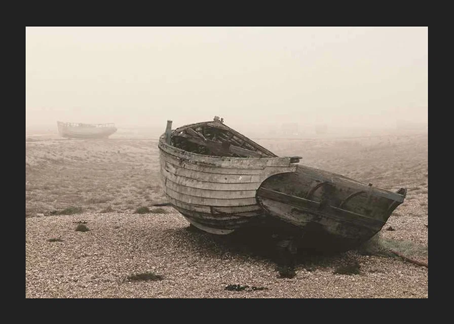 Photograph of old wooden boat on rocky beach in fog-12