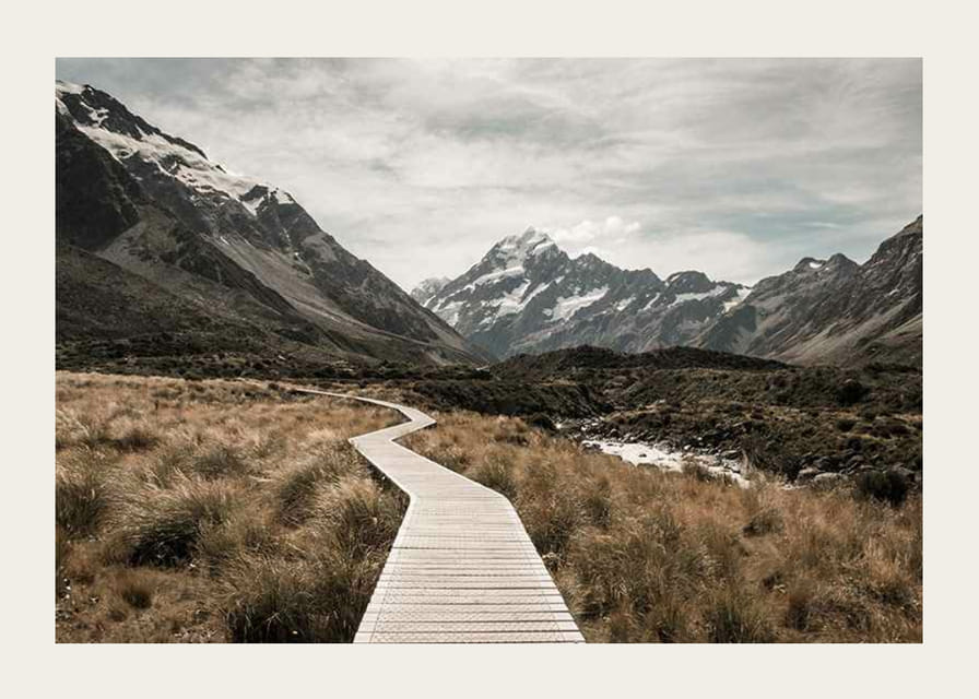 Fotografi av spång genom dal med snötäckta berg i bakgrunden-12