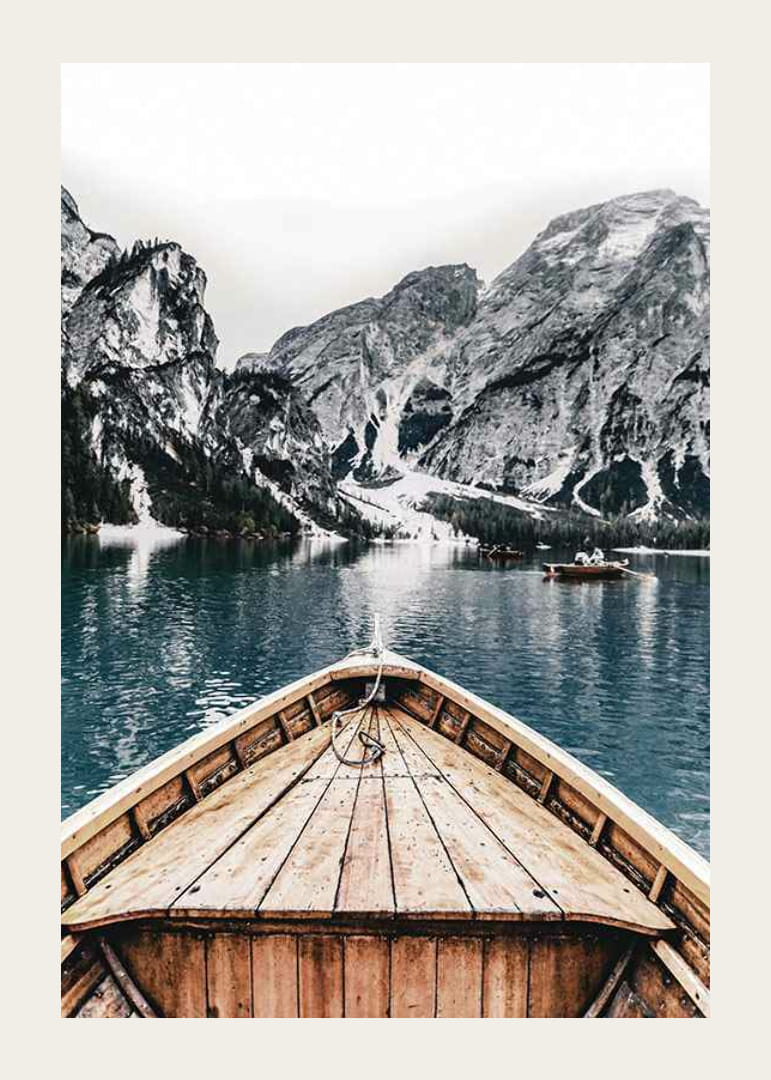 Fotografie eines Holzbootes auf türkisfarbenem Wasser vor schneebedeckten Bergen-12