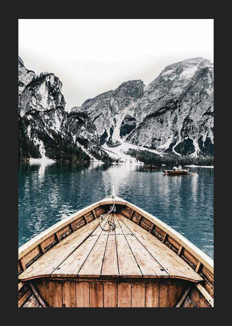 Fotografie eines Holzbootes auf türkisfarbenem Wasser vor schneebedeckten Bergen-12