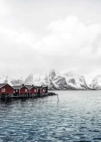 Photograph of red fishing huts by the water and snow-capped mountains-7