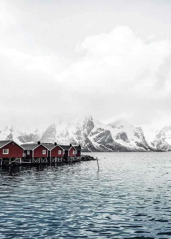 Photograph of red fishing huts by the water and snow-capped mountains-12