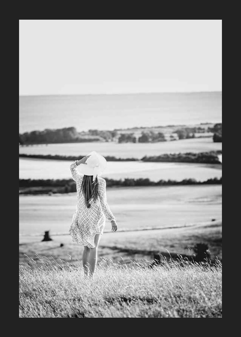 Black and white photograph of woman in dress in Danish countryside-12