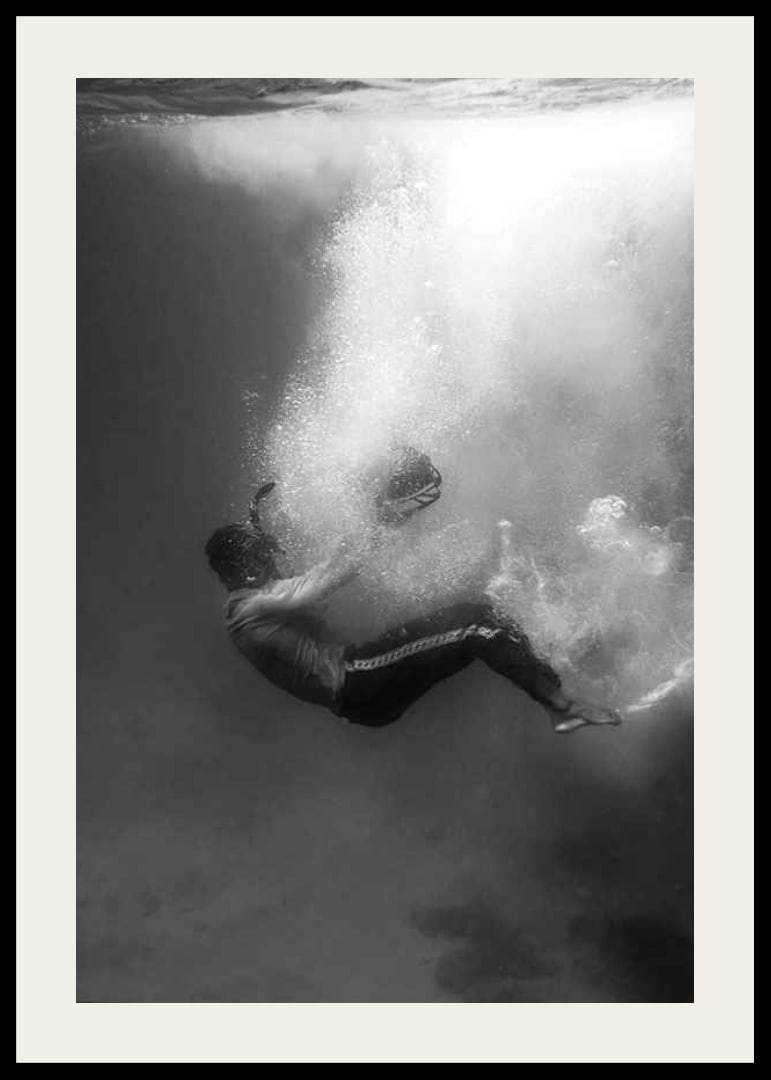 Black and white photograph of man sinking below water surface-12