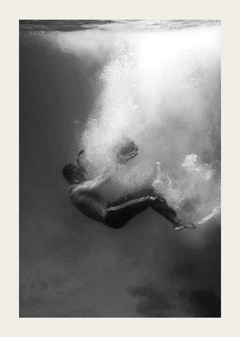Black and white photograph of man sinking below water surface-12