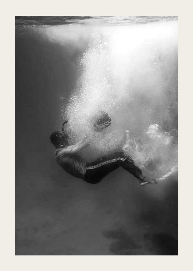 Zwart-witfoto van een man die onder het wateroppervlak zinkt-12