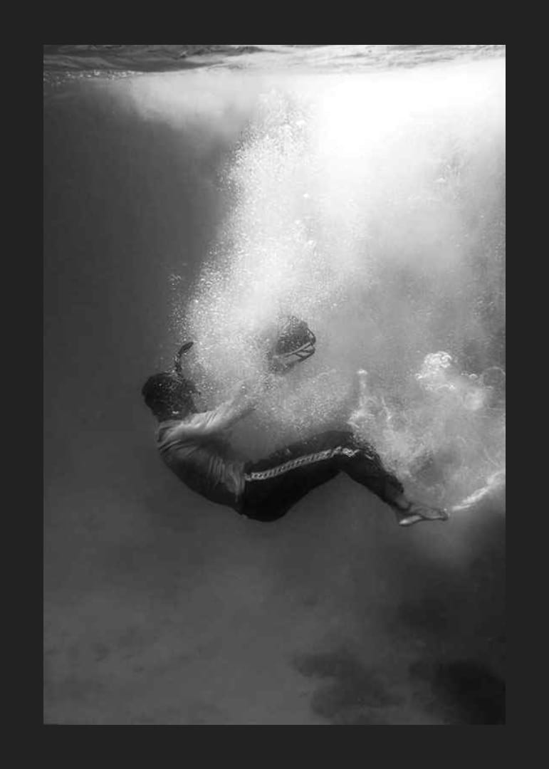 Zwart-witfoto van een man die onder het wateroppervlak zinkt-12