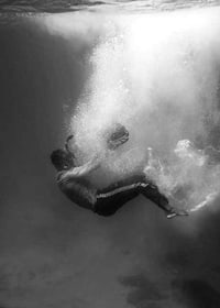 Black and white photograph of man sinking below water surface-7