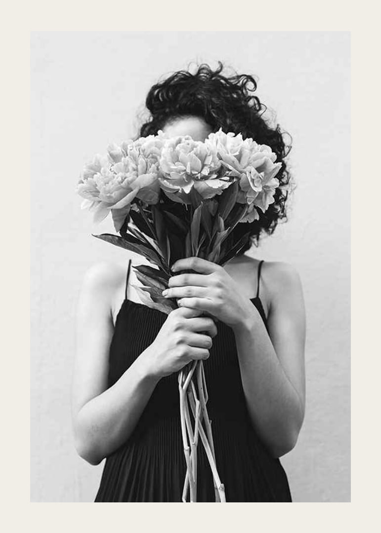 Schwarz-Weiß-Foto einer Frau mit lockigem Haar, die einen Blumenstrauß hält-12