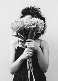 Schwarz-Weiß-Foto einer Frau mit lockigem Haar, die einen Blumenstrauß hält-7