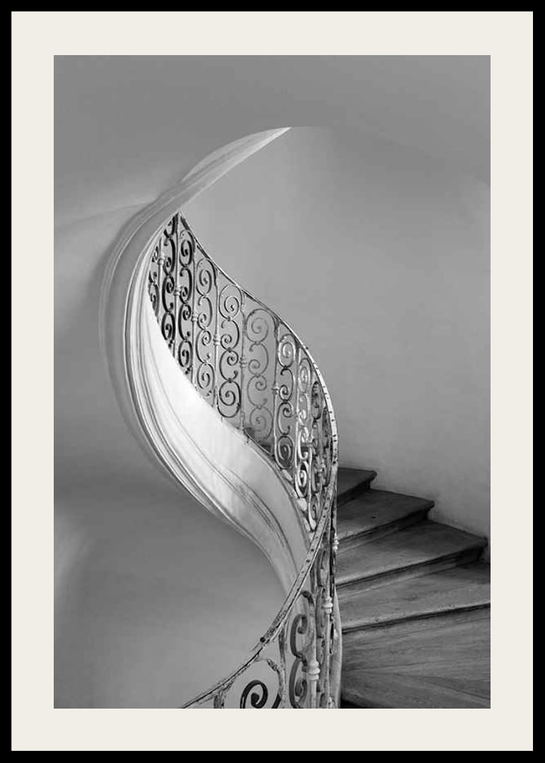 Black and white photograph of spiral staircase with wrought iron railing-12