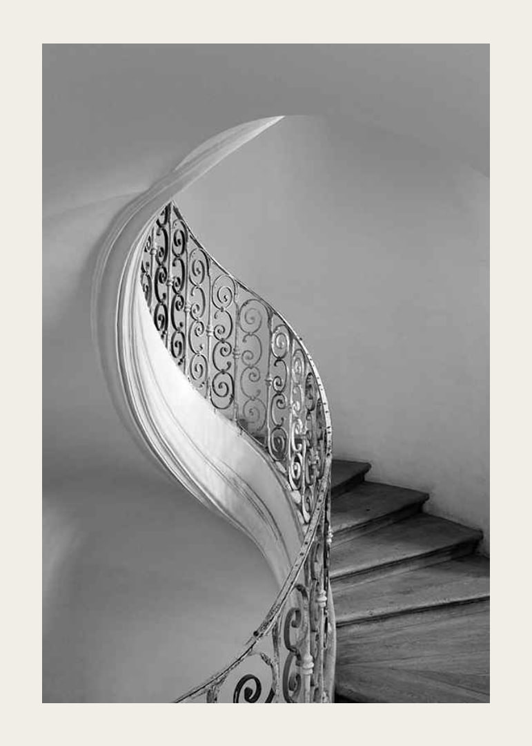Black and white photograph of spiral staircase with wrought iron railing-12