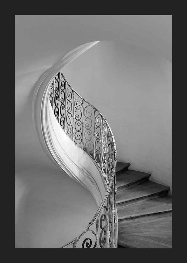 Zwart-witfoto van wenteltrap met smeedijzeren leuning-12