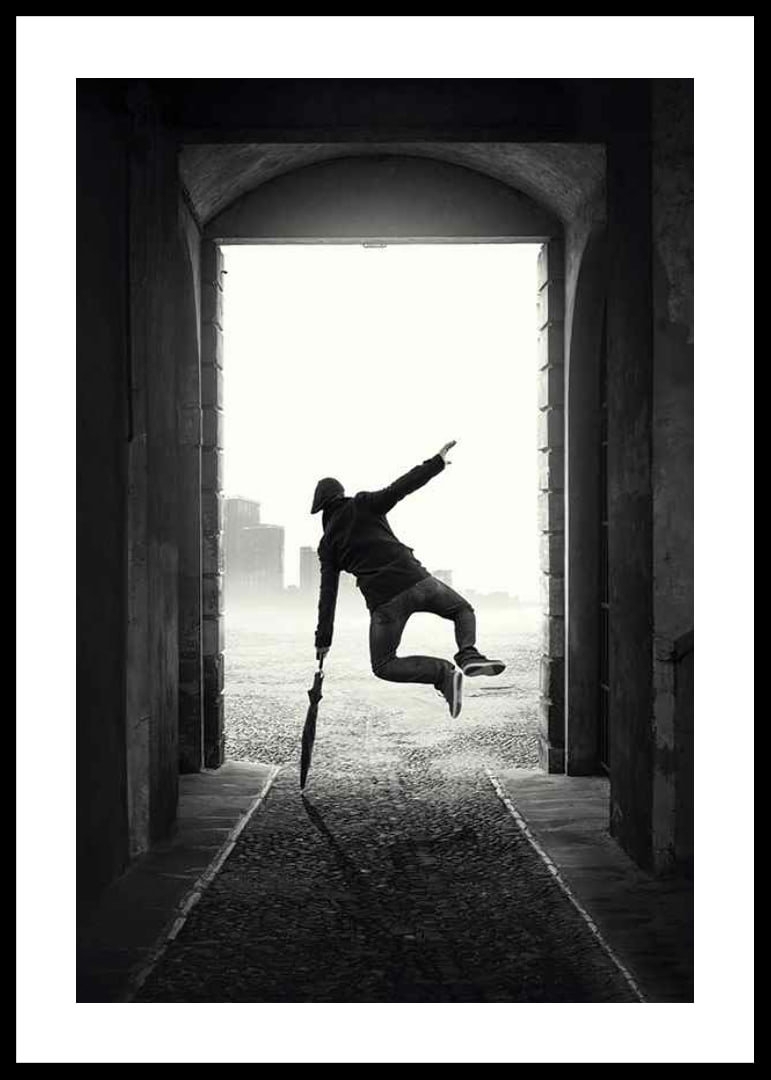 Black and white photograph of jumping man with umbrella in tunnel-12