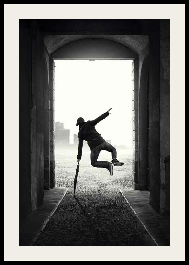Black and white photograph of jumping man with umbrella in tunnel-12