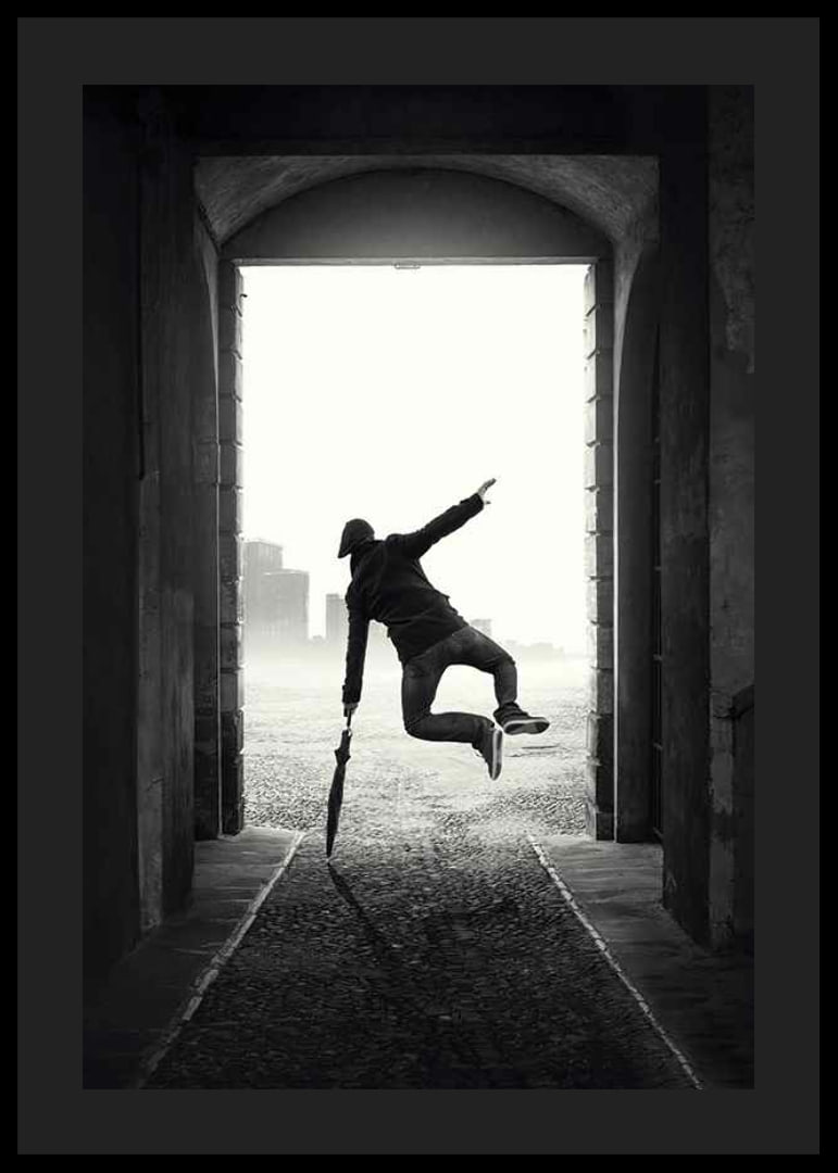 Black and white photograph of jumping man with umbrella in tunnel-12