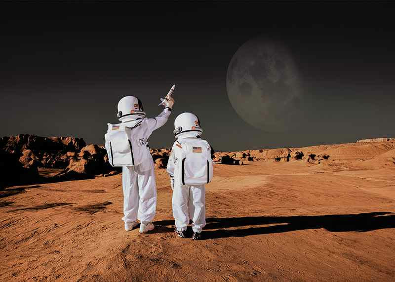 Two children in astronaut suits on red desert against dark sky-12