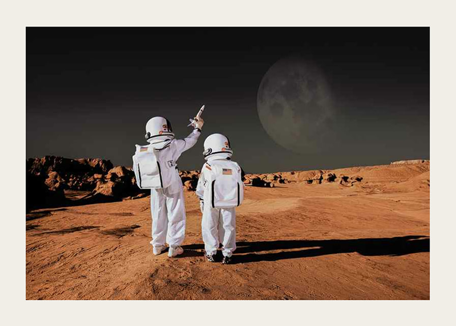 Two children in astronaut suits on red desert against dark sky-12