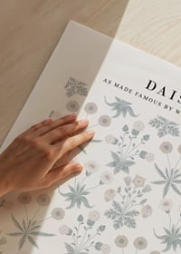 Dense, symmetrical pattern with stylized daisies in white and yellow and small green leaves against a muted blue background-3