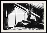 Black and white photograph of woman smoking in bed by window-2