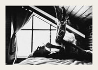Black and white photograph of woman smoking in bed by window-3