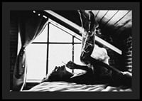 Black and white photograph of woman smoking in bed by window-4
