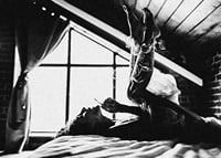 Black and white photograph of woman smoking in bed by window-7