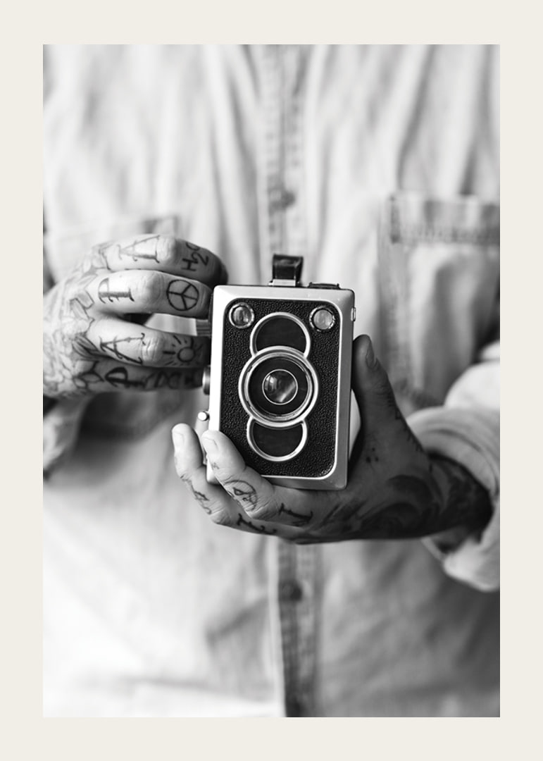 Black and white photo of tattooed hands holding a retro camera-12