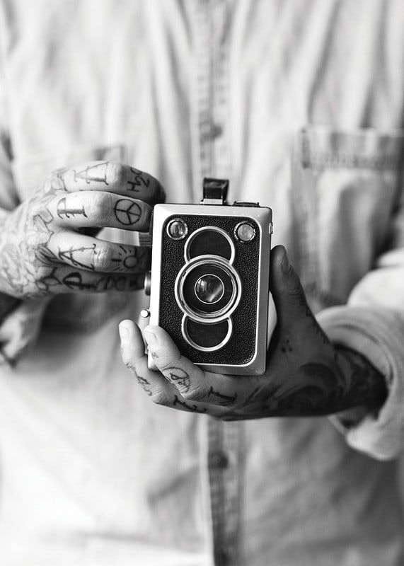 Black and white photo of tattooed hands holding a retro camera-12
